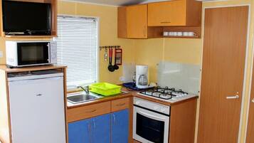 A compact kitchenette with a microwave, a coffee maker, a gas stove, and a sink.