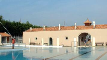 Una piscina con carriles delimitados, un edificio con arcos y un tejado de azulejos.