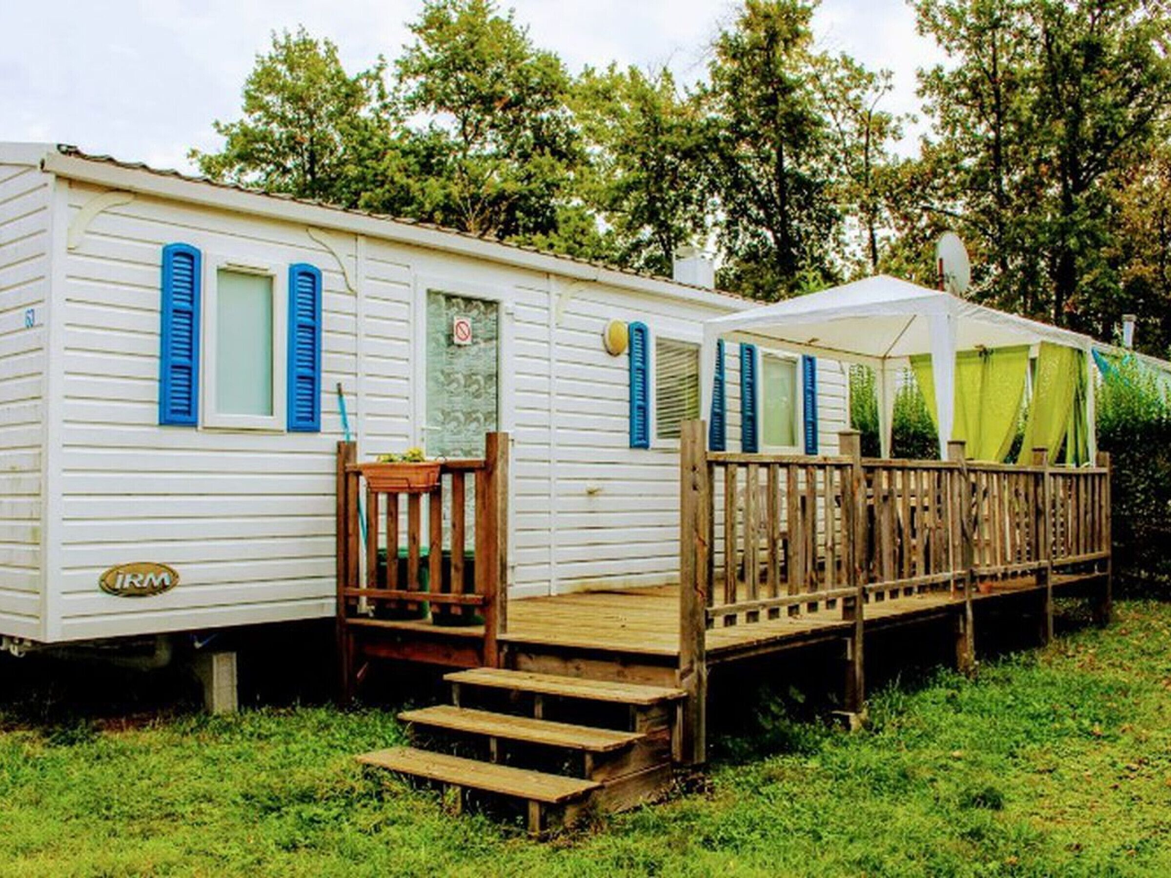 A mobile home with a wooden deck and steps leading to the entrance.