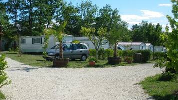 A gravel parking area with a car and a mobile home.