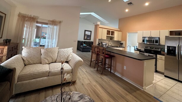 Una cocina moderna con una isla central, una zona de comedor con sofá y un ventilador de techo.