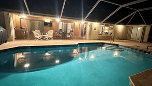 Piscina con sillas de descanso y un patio cubierto.