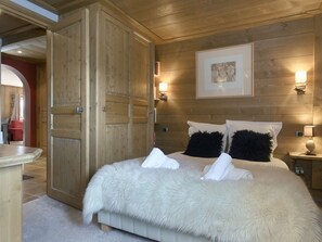 Ein Schlafzimmer mit einem großen Bett, einem Holzschrank und Wandleuchten.