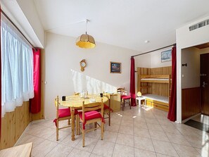 Ein Zimmer mit einem Holzesstisch, Stühlen, einem Etagenbett und einer Hängelampe.