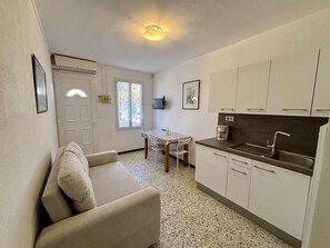 A compact living space with a kitchenette, a dining area, and a sofa. - Air-conditioned apt near beach - 4 guests (Port-la-Nouvelle)