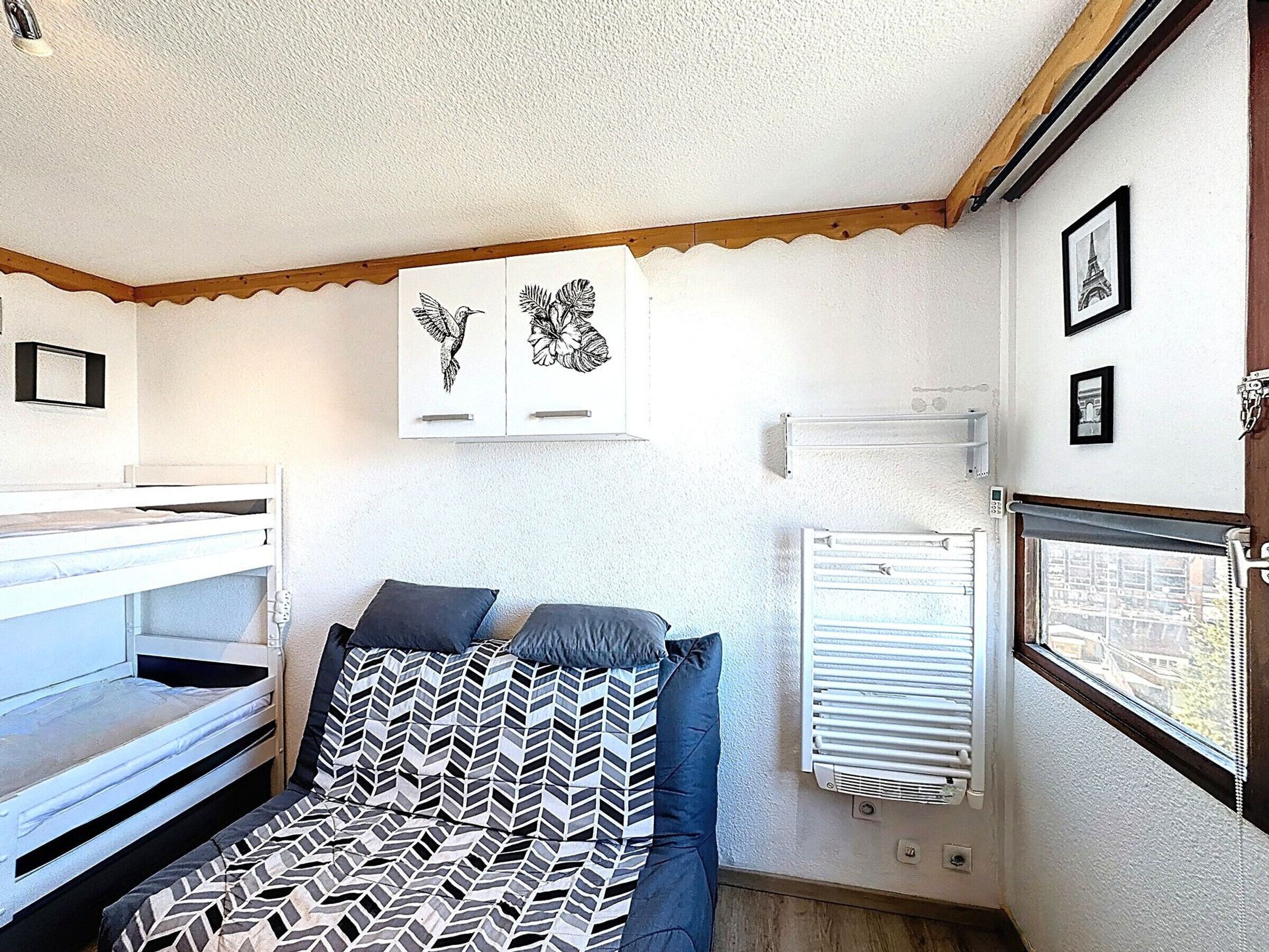 A compact room with bunk beds, a radiator, and two framed pictures on the wall.