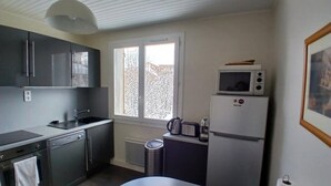 Una cocina compacta con armarios oscuros, un lavamanos, un microondas y un refrigerador.