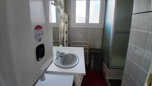 Un baño pequeño con un lavamanos blanco, un espejo y una ventana.