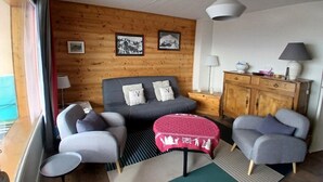 Una habitación acogedora con una cama, dos sillones, una mesita, un armario y una ventana con cortinas.