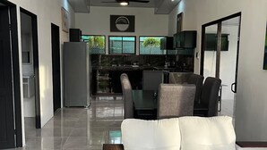Ein modernes Wohnzimmer mit einer Couch, einem Esstisch und einer Küche im Hintergrund.