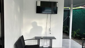 Ein modernes Zimmer mit Wandfernseher, einem Tisch, einem Stuhl und Fliesenboden.