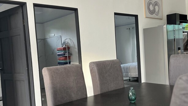 Ein Konferenzraum mit dunklem Tisch, grauen Stühlen, einer kleinen Vase und einem Kühlschrank.