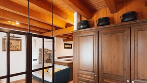 Un interior de madera con una cama, un armario y una pared de piedra.