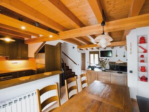 Een houten interieur met een keuken, een eethoek en een trap.