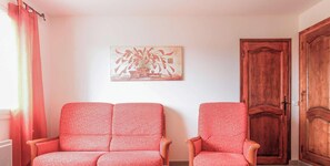 Una habitación con dos sillones estampados, una puerta de madera y una obra de arte colgada en la pared.