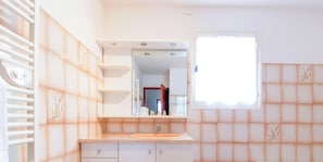 Un baño con lavamanos, espejo y ventana.