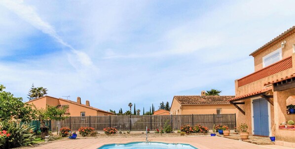 Zona residencial con piscina, casas con tejados de tejas y cielo despejado.