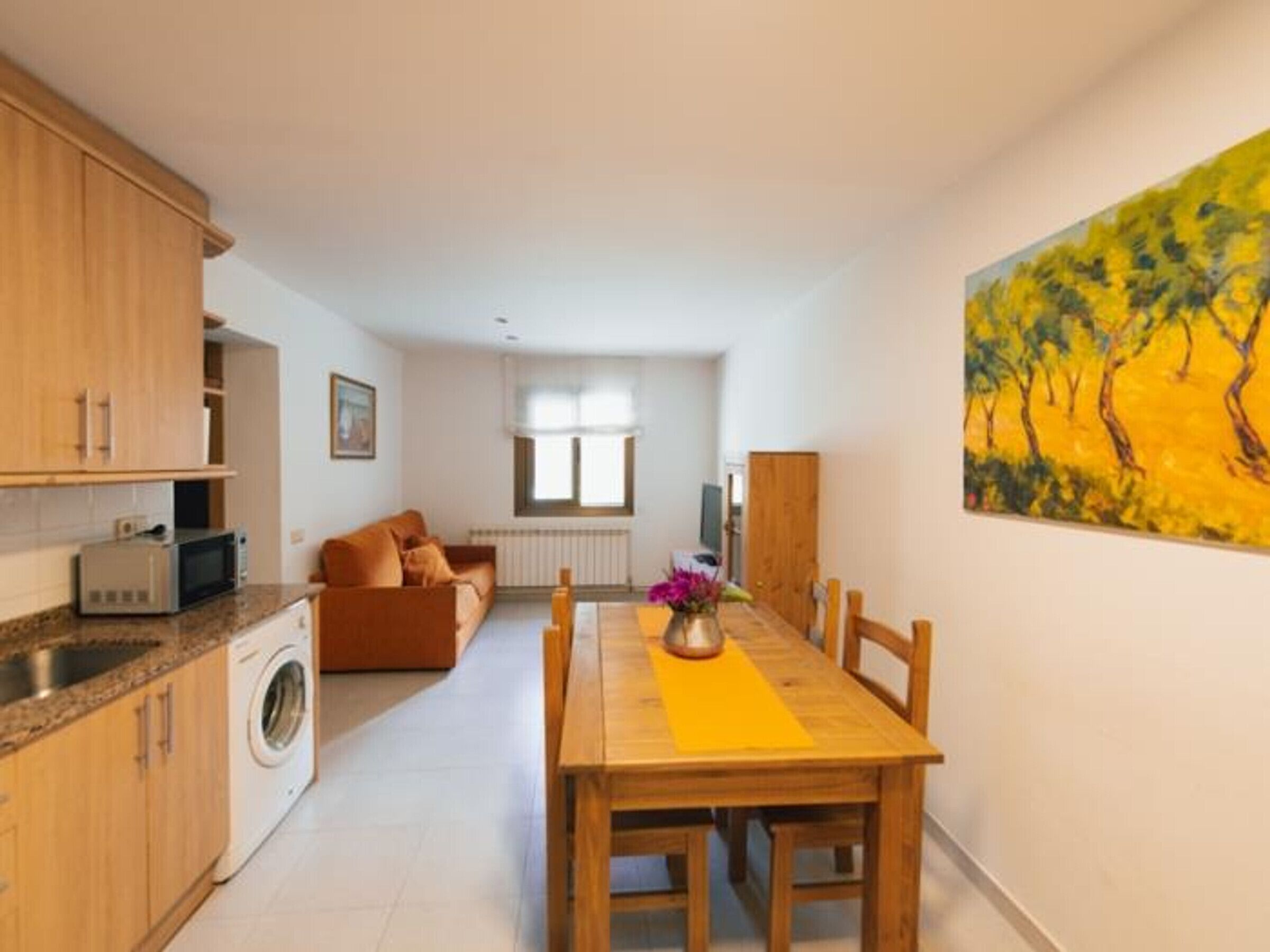 Um espaço compacto com cozinha, sala de jantar e sofá.