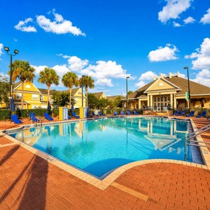 A swimming pool with lounge chairs, palm trees, and buildings in the background. - Disney Dream~Resort Pool & Water Park Fun~Hot Tub (Kissimmee)