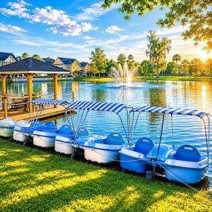 Une rangée de pédalos équipés de toits, un kiosque et une fontaine au bord d’un lac.