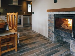 Une cuisine moderne avec une cheminée en pierre, des chaises en bois et une table à manger.