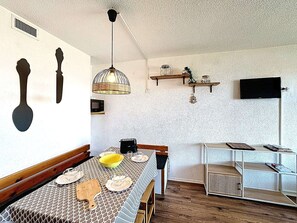 Ruokailutila, jossa on kuvioitu pöytäliina, puinen penkki ja katosta roikkuva valaisin.