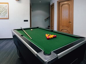 Een pooltafel met ballen en een keu, een houten deur en een lijst met een foto aan de muur.