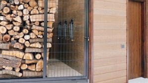 A wooden cabin with a metal door, a stack of firewood, and a metal gate. - Cozy House near Aigüestortes Park, 6 ppl, Pets welcome (Espot)
