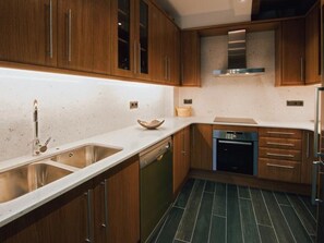 Een moderne keuken met houten kastjes, een RVS spoelbak en een vaatwasser.