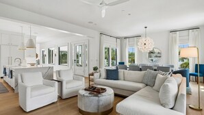 A spacious living room with a large sectional sofa, a round coffee table, and a dining area with a white table and chairs. - The Ivory Tide by Charleston Vacays (Isle of Palms)
