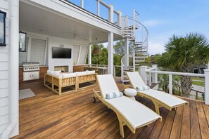 Eine Terrasse im Freien mit Grill, Sitzgelegenheit und Fernseher.