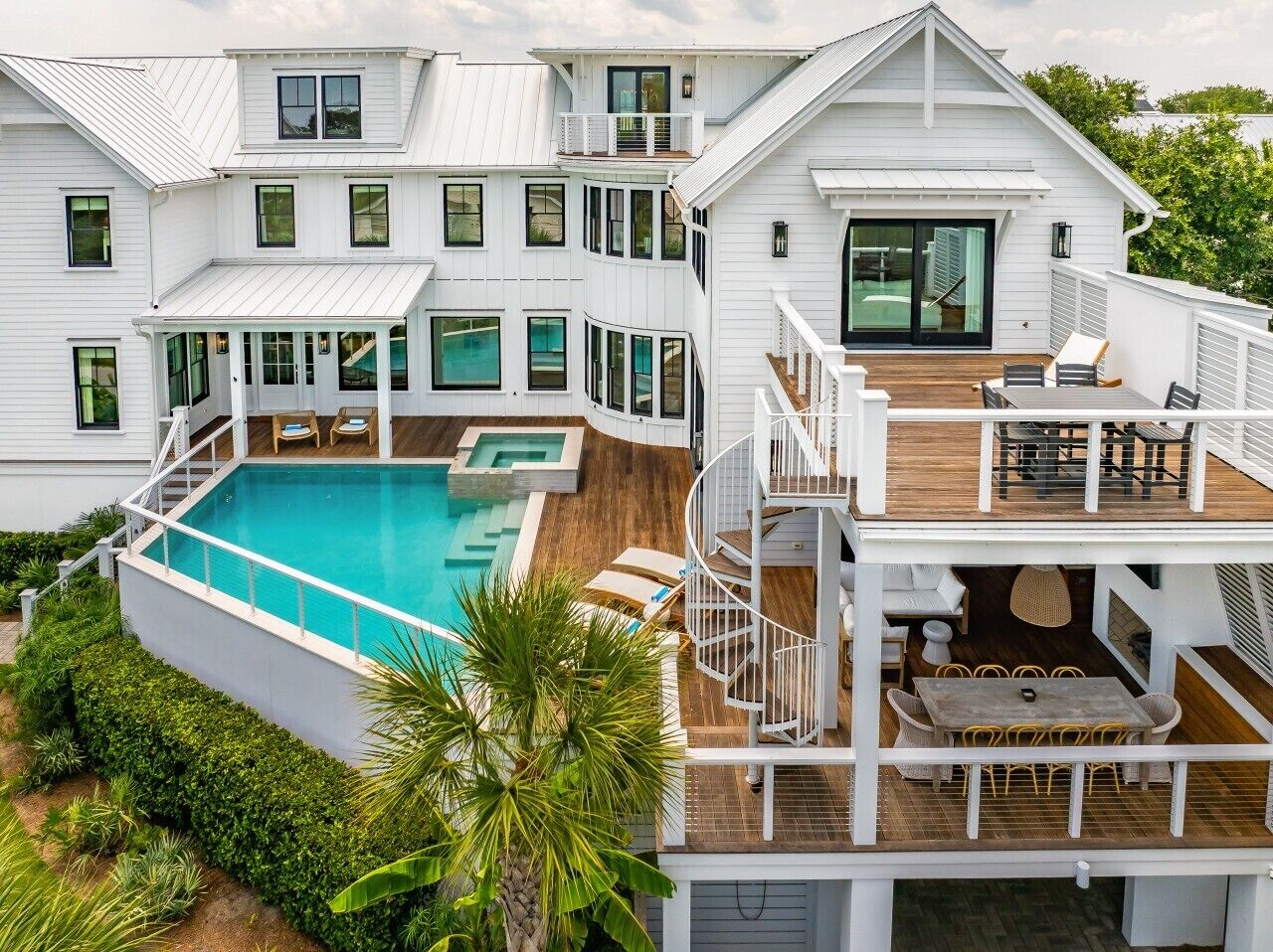 A two-story house with a swimming pool, outdoor seating, and a staircase connecting the levels.