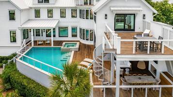 A two-story house with a swimming pool, outdoor seating, and a staircase connecting the levels.