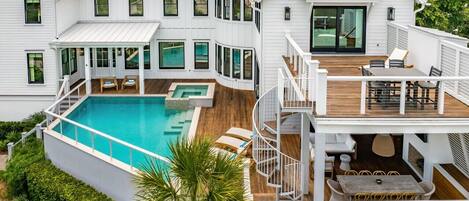 A two-story house with a swimming pool, outdoor seating, and a staircase connecting the levels.