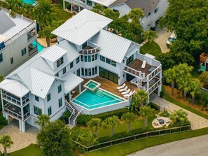 A modern multi-story house with a large swimming pool, multiple balconies, and lush landscaping. - The Ivory Tide by Charleston Vacays (Isle of Palms)
