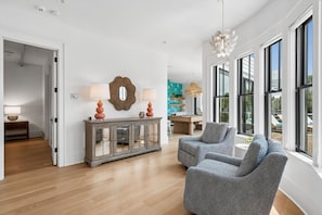 Een ruime woonkamer met een moderne open haard, een eettafel en een groot raam met uitzicht op de omgeving.