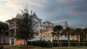 A multi-story house with a balcony, a well-maintained lawn, and a clear sky. - The Ivory Tide by Charleston Vacays (Isle of Palms)