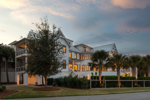 A multi-story house with a balcony, a well-maintained lawn, and a clear sky. - The Ivory Tide by Charleston Vacays (Isle of Palms)