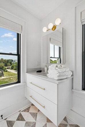 Ein modernes Badezimmer mit einem großen Fenster, einem Waschbecken mit Spiegel und einem Handtuchhalter.