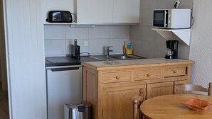 Eine kleine Küche mit Geschirrspüler, Spüle, Mikrowelle und Kaffeemaschine.