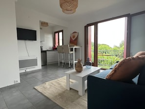 Ein modernes Wohnzimmer mit einer Couch, einem Couchtisch und einer Küche im Hintergrund.
