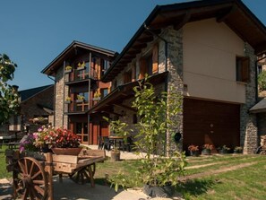 Un edificio de varios pisos con fachada de piedra, balcones y un espacio de estar al aire libre techado.