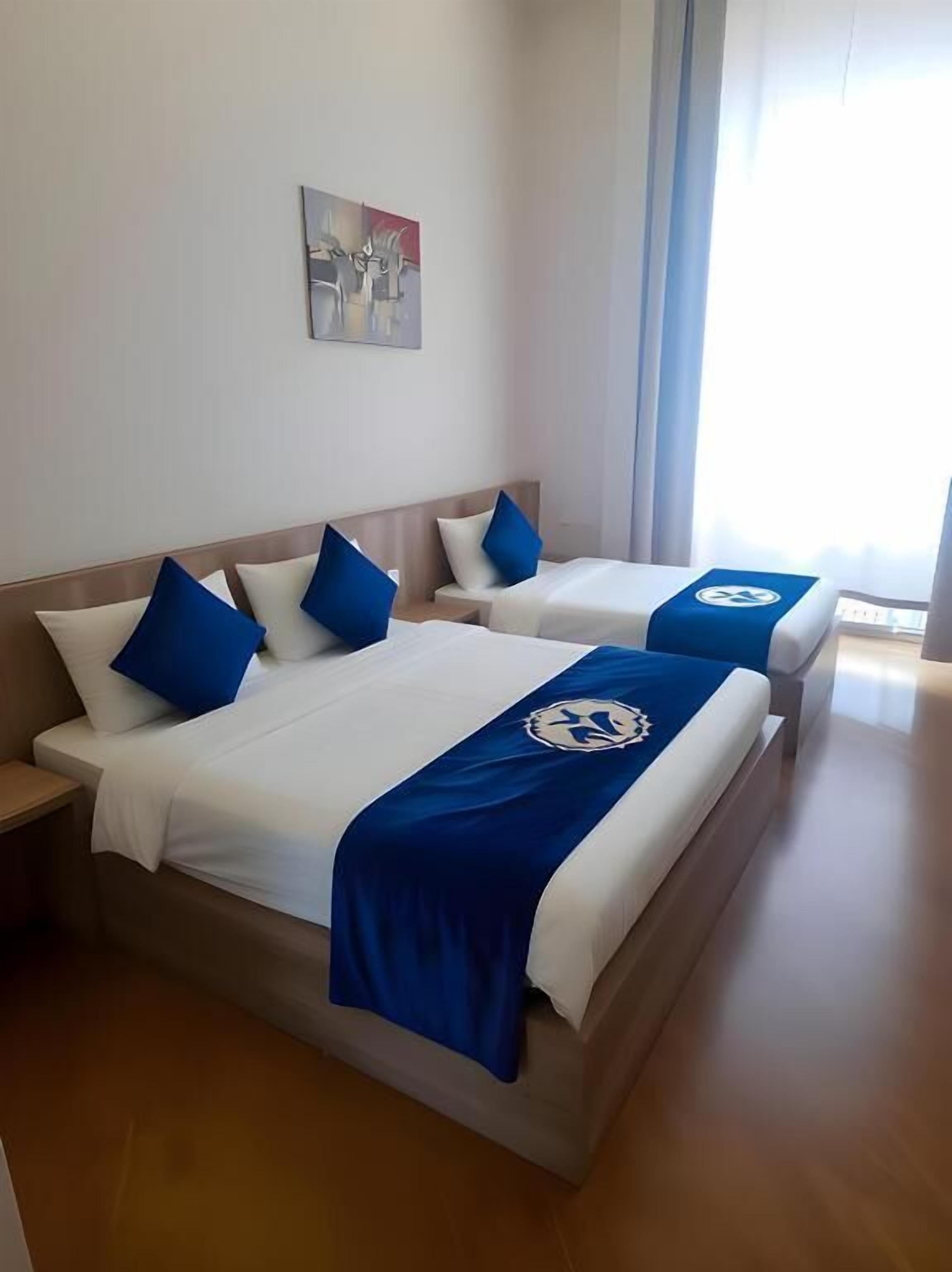 A hotel room with two beds, each with a blue and white bedspread and matching pillows.