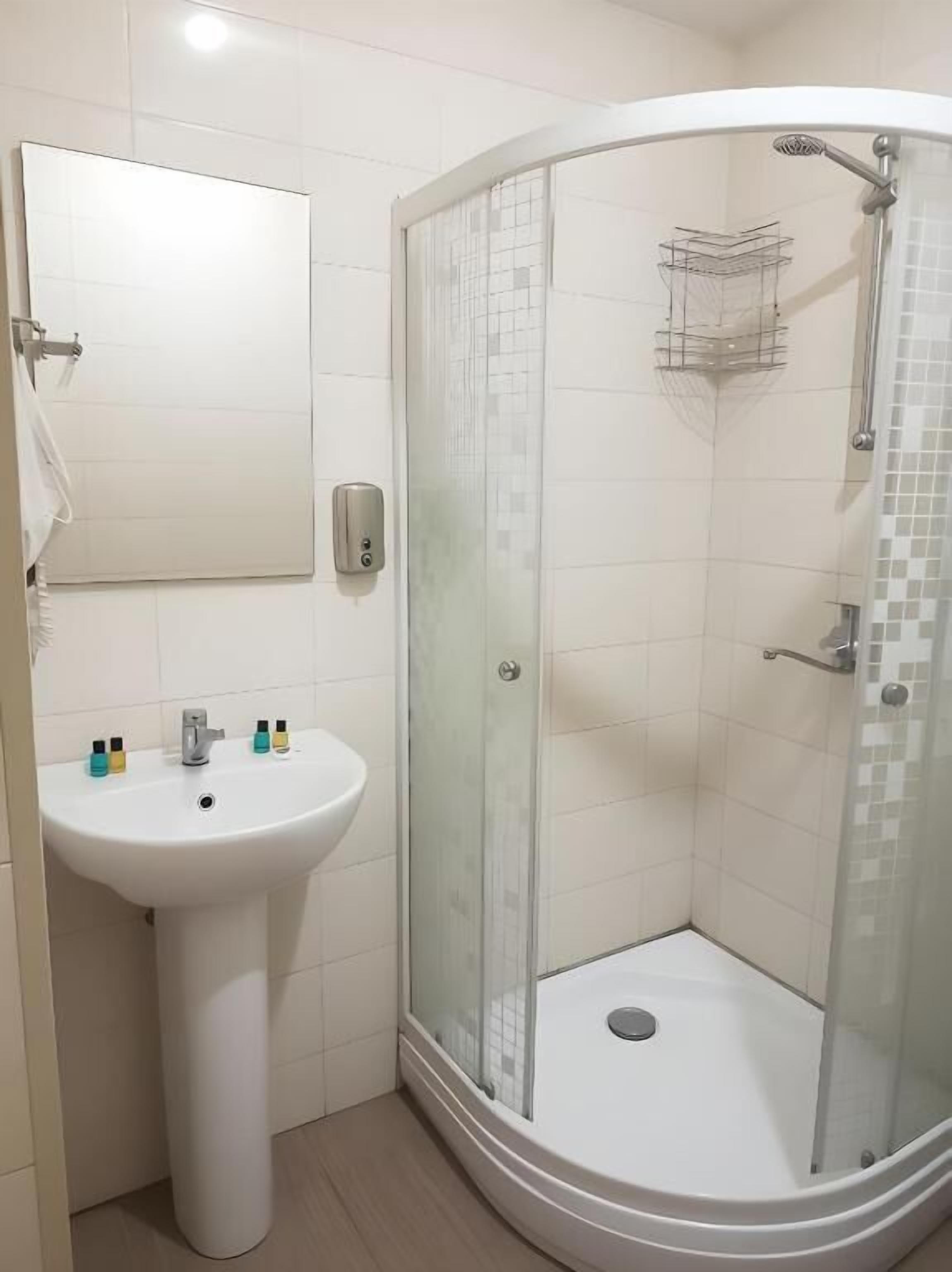 A bathroom with a white sink, a glass shower enclosure, and a mirror.