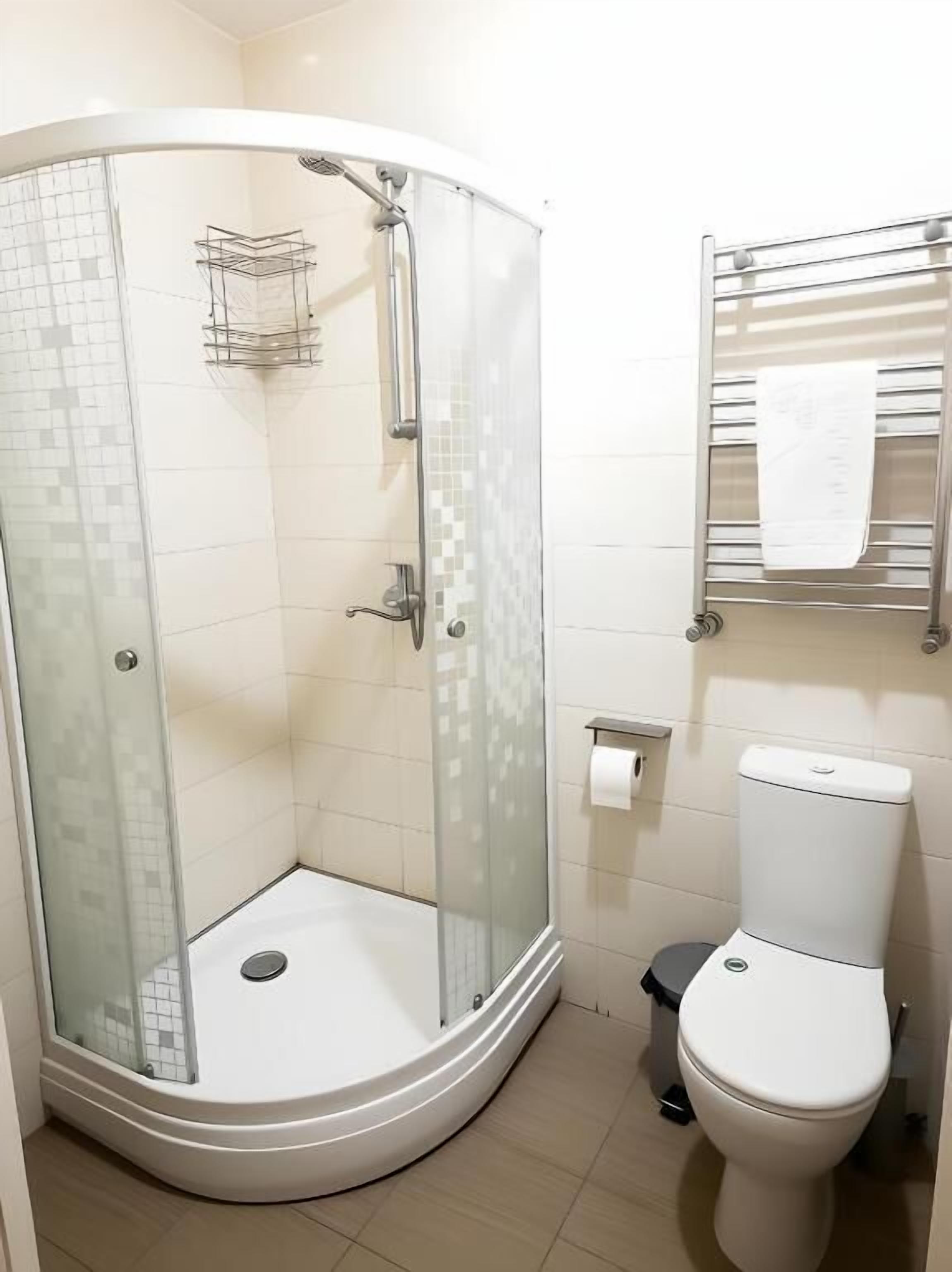 A bathroom with a glass-enclosed shower, a toilet, and a towel rack.