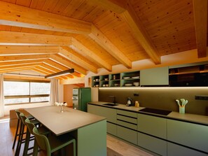 Een moderne keuken met houten balken, groene kasten en een centraal eiland.