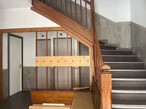 A wooden staircase with a handrail, a landing with a wooden bench, and a door with a number. - Cozy apartment in the heart of Cauterets - 4 guests (Cauterets)