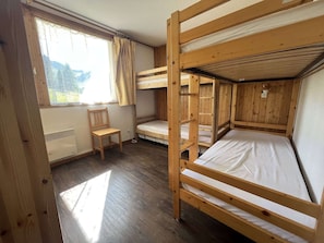 Ein Zimmer mit Etagenbetten, einem Stuhl und einem Fenster mit Vorhängen.
