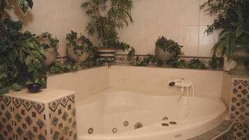 Une salle de bain avec une baignoire sur pieds, des murs carrelés et des plantes en pot.