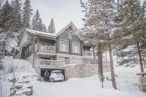 A multi-story building with a stone facade, balconies, and a car parked in front. - Passoo - Boutique hotel & sauna (Tahkovuori)